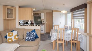 Un espacio habitable compacto con kitchenette, comedor y sofá con cojines estampados.