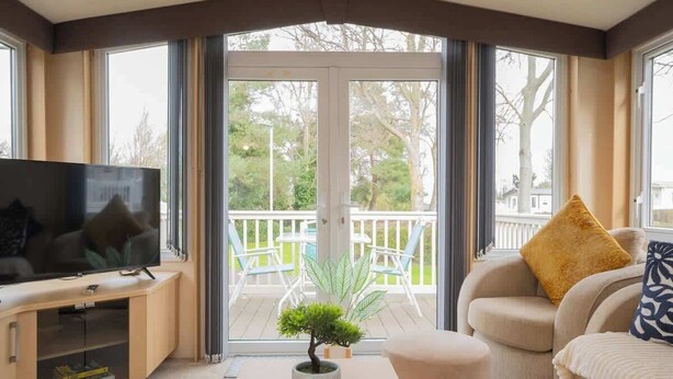 Una sala de estar con televisor, sofá, mesa de centro y una planta en maceta.