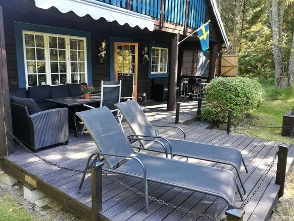 A wooden deck with lounge chairs, a table, and a flag.
