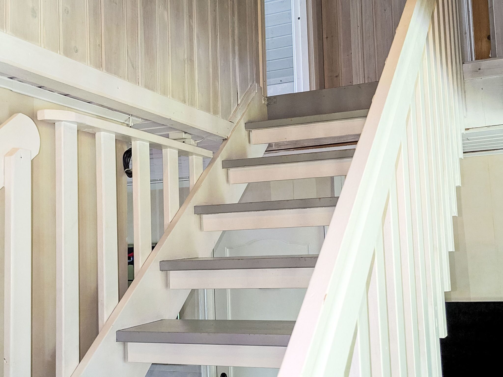 Una escalera con barandillas blancas y escalones de madera.