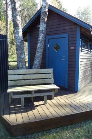 A wooden bench outside a building with a blue door.