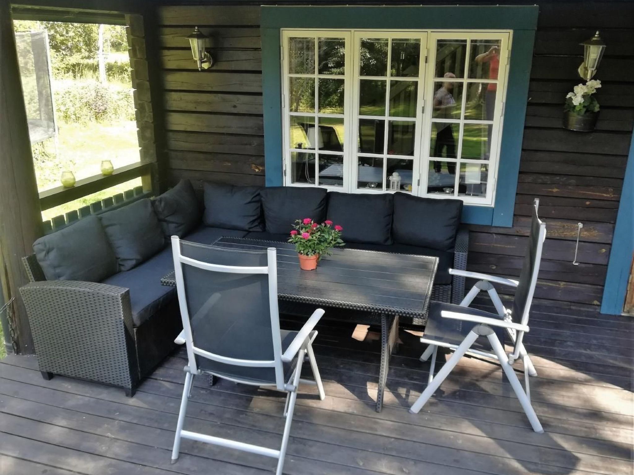 Een terras buiten met een donkergrijze bank, een klein rond tafeltje en witte stoelen.