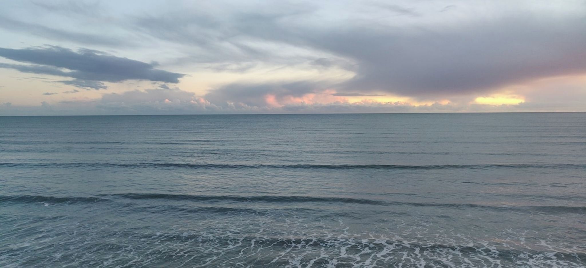 A calm sea with gentle waves and a cloudy sky.