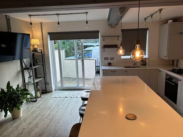 A modern kitchen with a large island, pendant lighting, and a sliding glass door leading to a patio.