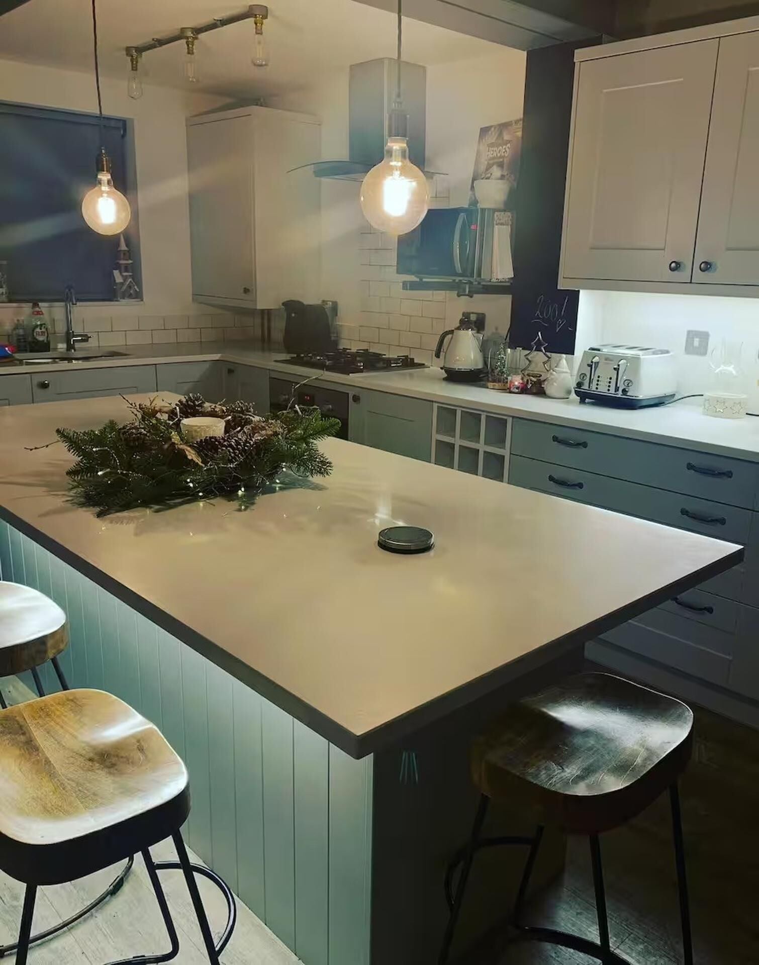 Une cuisine moderne dotée d’un îlot central, de tabourets de bar, de luminaires suspendus et d’un grille-pain.