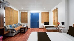 A hotel room with a bed, a sofa, a small table, a fan, a blue door, and a telephone. - Premiumjannat Residency (Jodhpur)