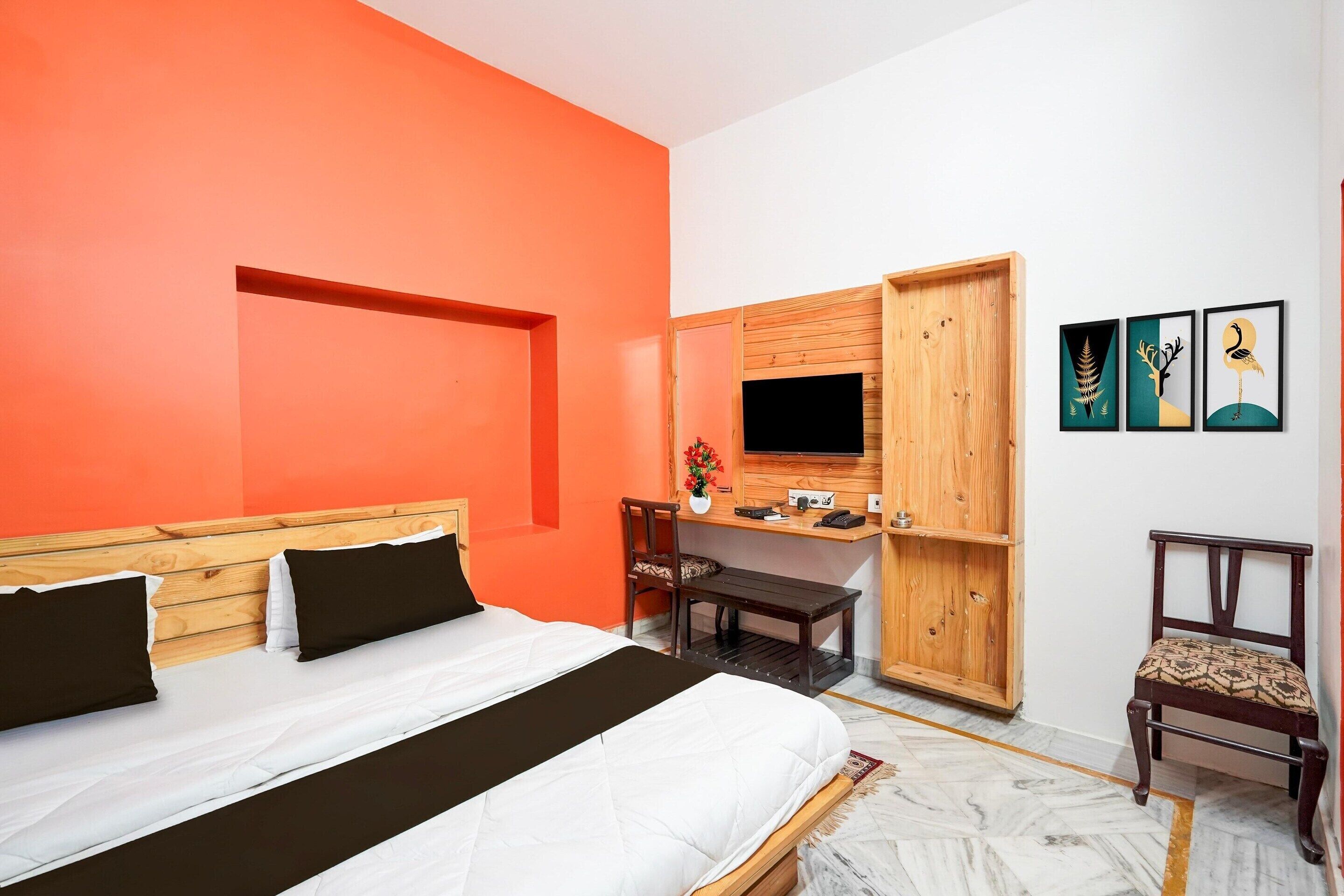 Ein Schlafzimmer mit Bett, Schreibtisch, Sessel, Fernseher und Bildern an der Wand.