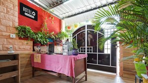 A room with a red wall, a sign reading 'HOTEL,' a table with a pink tablecloth, and various plants. - Premiumjannat Residency (Jodhpur)