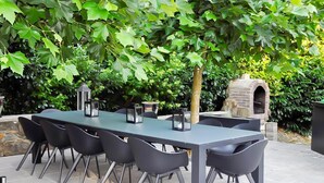 A dining area with a long table, black chairs, and lanterns. - Luxury Ardennes Villa With Pool and Sauna (Stoumont)