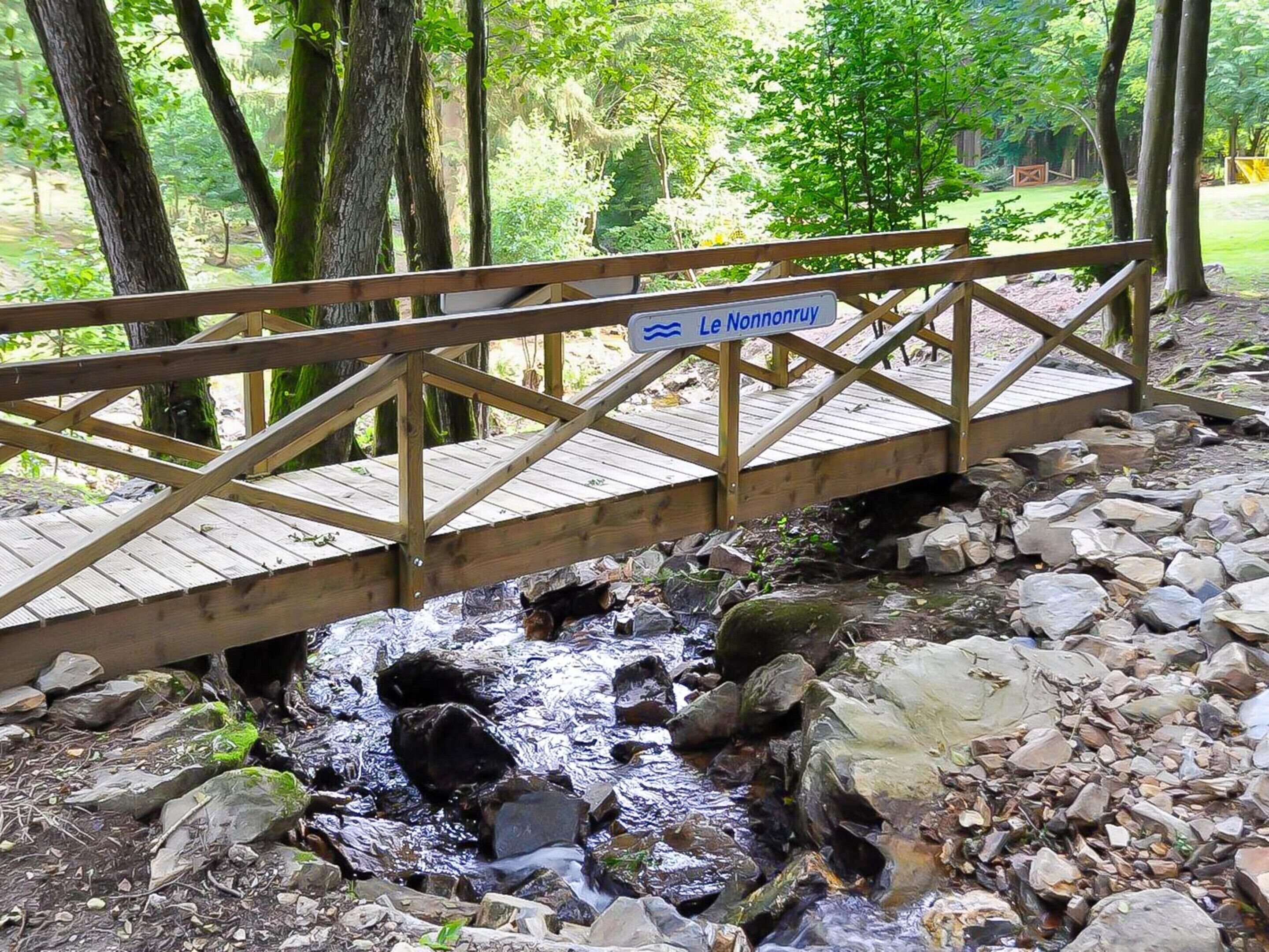 A wooden bridge over a rocky stream with a sign reading 'Le Nonnenkloof.'