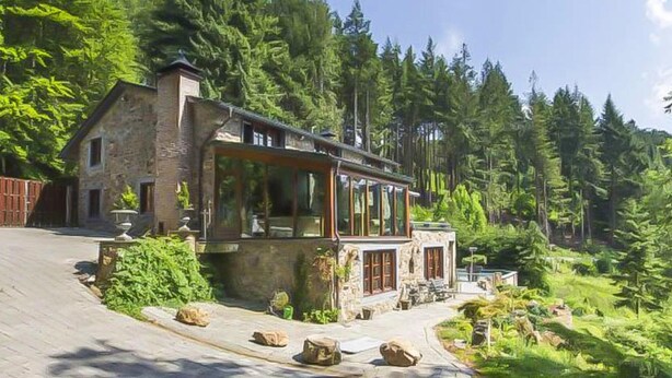 A stone house with large windows, surrounded by dense forest. - Luxury Ardennes Villa With Pool and Sauna (Stoumont)