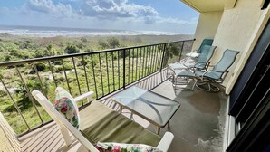 Ein Balkon mit Blick auf den Ozean, einem Tisch und zwei Stühlen.