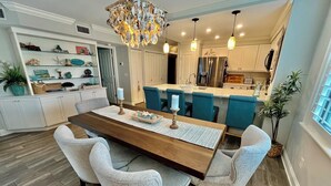 Une cuisine moderne avec des meubles blancs, un îlot central et des luminaires suspendus.
