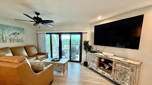 Ein Wohnzimmer mit Sofa, Couchtisch, Fernseher und Schrank.