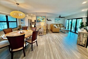 A modern living room with a dining area, a kitchen, and a balcony with large windows. - Enjoy upgraded amenities in this stunning Gold-rated condo with views overlooking the pool and ocean. (Saint Augustine)