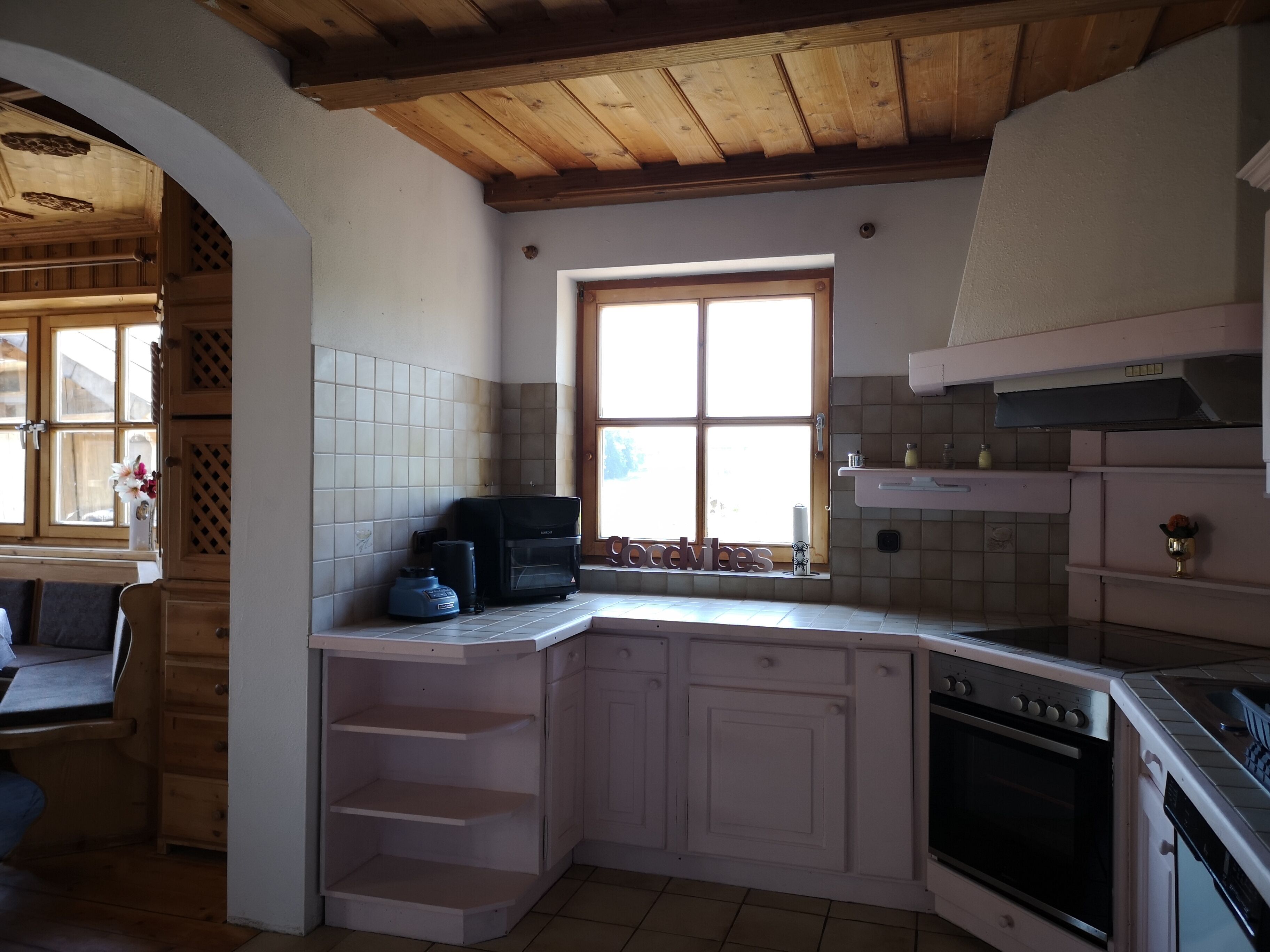 A kitchen with white cabinets, a built-in oven, a coffee maker, and a window with a view.