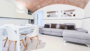 A modern interior with a dining area, a grey sofa, and a brick ceiling. - Welcome to Il Giardino di Bryan, a peaceful oasis in the heart of La Spezia, perfect for those who want to enjoy the city while relaxing in a green and quiet environment.The house enjoys a strategic location, just 5 minutes’ walk from the train station (La Spezia)