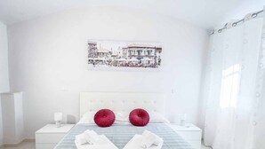 A hotel room with a bed, a nightstand, a bedside table, a picture on the wall, and a window with curtains. - Welcome to Il Giardino di Bryan, a peaceful oasis in the heart of La Spezia, perfect for those who want to enjoy the city while relaxing in a green and quiet environment.The house enjoys a strategic location, just 5 minutes’ walk from the train station (La Spezia)