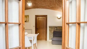 A room with a dining table and chairs, a sofa, a wooden door, and a stone wall. - Welcome to Il Giardino di Bryan, a peaceful oasis in the heart of La Spezia, perfect for those who want to enjoy the city while relaxing in a green and quiet environment.The house enjoys a strategic location, just 5 minutes’ walk from the train station (La Spezia)