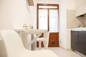 A kitchen with a white table and chair, a wooden door with heart-shaped decorations, and a tiled backsplash. - Welcome to Il Giardino di Bryan, a peaceful oasis in the heart of La Spezia, perfect for those who want to enjoy the city while relaxing in a green and quiet environment.The house enjoys a strategic location, just 5 minutes’ walk from the train station (La Spezia)