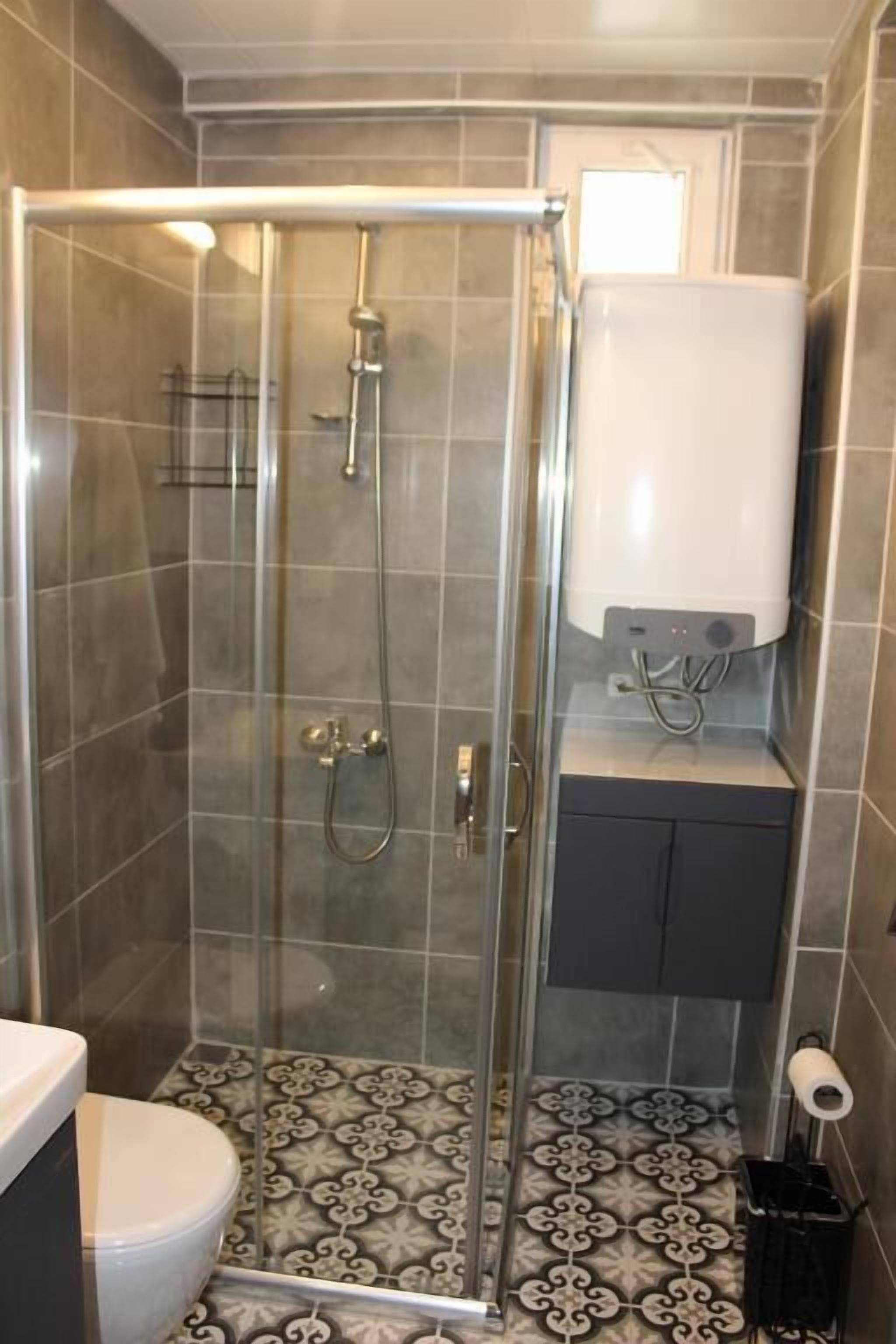 Suihkukaappi lasiovella, wc ja pyyheteline.