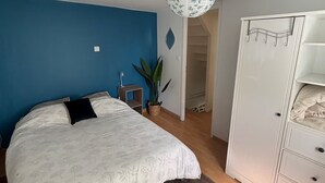 Une chambre à coucher avec un lit, une armoire, une plante en pot et un luminaire suspendu.