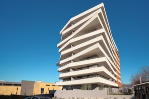 A modern multi-story building with balconies, large windows, and a clear sky. - Superior apartment with balcony (Split)