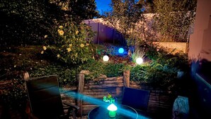 An outdoor seating area with a table and chairs, surrounded by lush greenery and a wooden fence. - Cozy quiet apartment in Berlin with terrace, free parking (Berlin)
