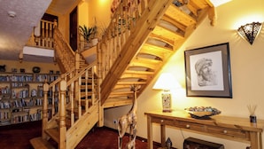 A wooden staircase with a bookshelf and a framed artwork on the wall. - Dunhallin House (Inverness)