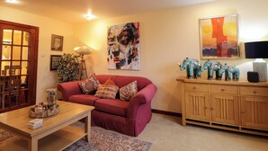 A living room with a red sofa, wooden cabinet, and artwork on the walls. - Dunhallin House (Inverness)