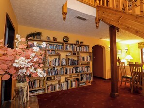 A library with bookshelves, a wooden staircase, and a Buddha statue. - Dunhallin House (Inverness)