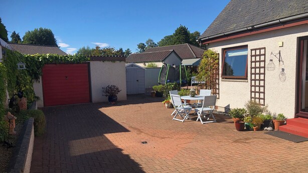 A patio area with a brick floor, a white table with chairs, and potted plants. - Dunhallin House (Inverness)