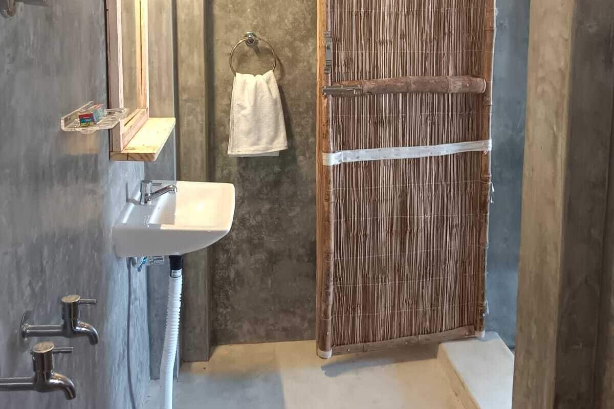 A bathroom with a wooden shower enclosure, a sink with a mirror, and a towel hanging on the wall.
