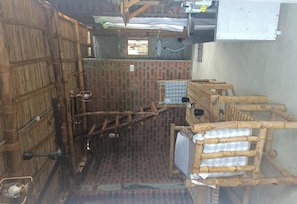 A rustic bathroom with a brick wall, wooden furniture, and a bamboo door.