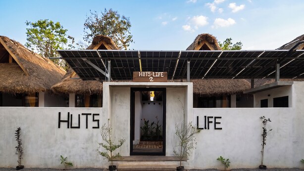 A building with a sign reading 'HUTS-LIFE 2' and solar panels on the roof. - Huts Life Home Stay (Vanur)