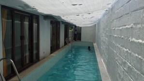 An indoor swimming pool with clear water, a ladder, and a covered ceiling. - Huts Life Home Stay (Vanur)