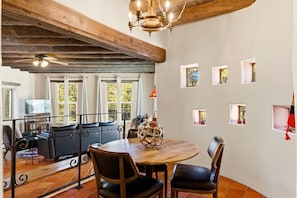 A dining area with a round wooden table, black leather chairs, and a decorative sphere centerpiece.