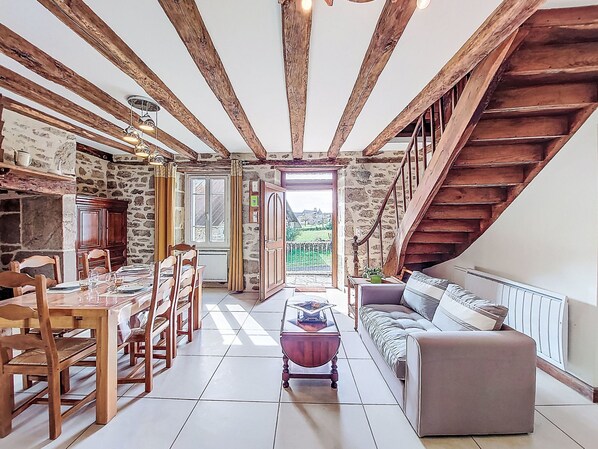A dining area with wooden chairs and a table, a sofa, a coffee table, and a staircase leading to an upper level. - Gîte Saint Sauveur by Interhome (St-Martin-La-Meanne)