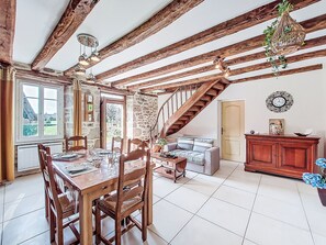 A rustic dining area with exposed wooden beams, a staircase, a stone wall, and a view through a window. - Gîte Saint Sauveur by Interhome (St-Martin-La-Meanne)