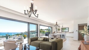 Ein modernes Wohnzimmer mit einer Couch, einem Glastisch und einer Pendelleuchte.