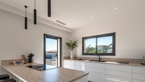 Eine moderne Küche mit Kochinsel, weißen Schränken und einem großen Fenster mit Blick.