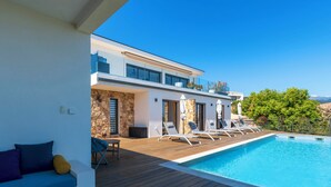Ein moderner Poolbereich mit Holzdeck, Liegestühlen und einem klaren, blauen Pool.