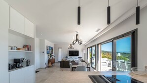 Eine moderne Küche mit Essbereich, Wohnzimmer und einer großen Schiebeglasdoor zu einem Balkon.