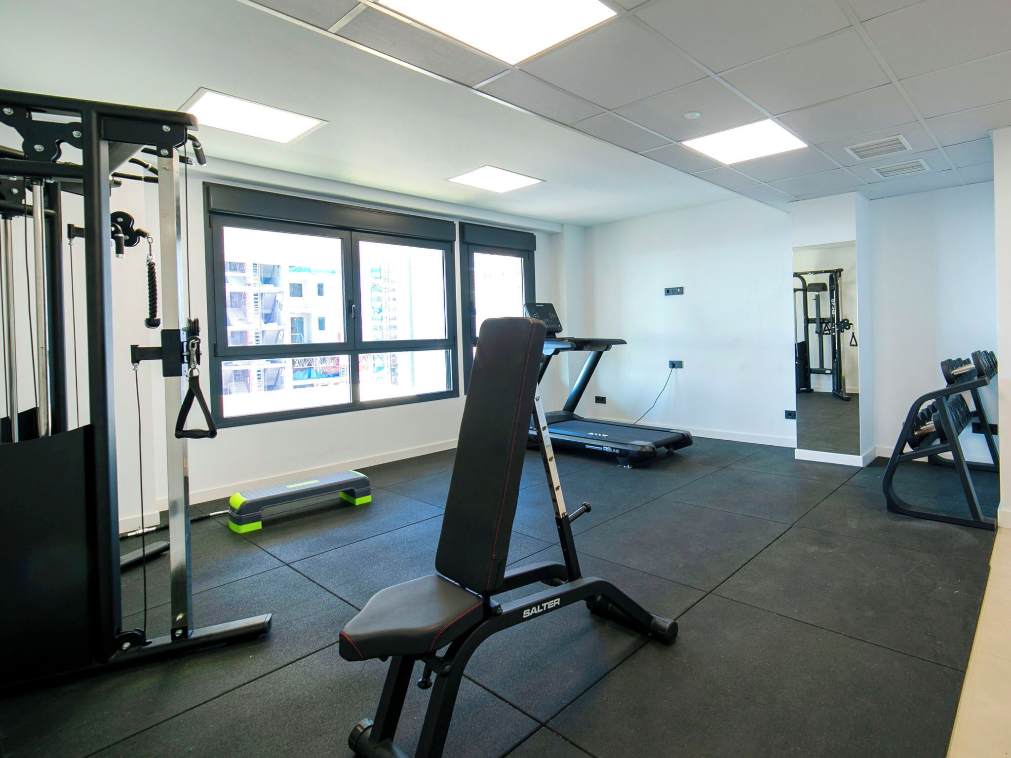 A gym with a treadmill, weight bench, and exercise equipment.