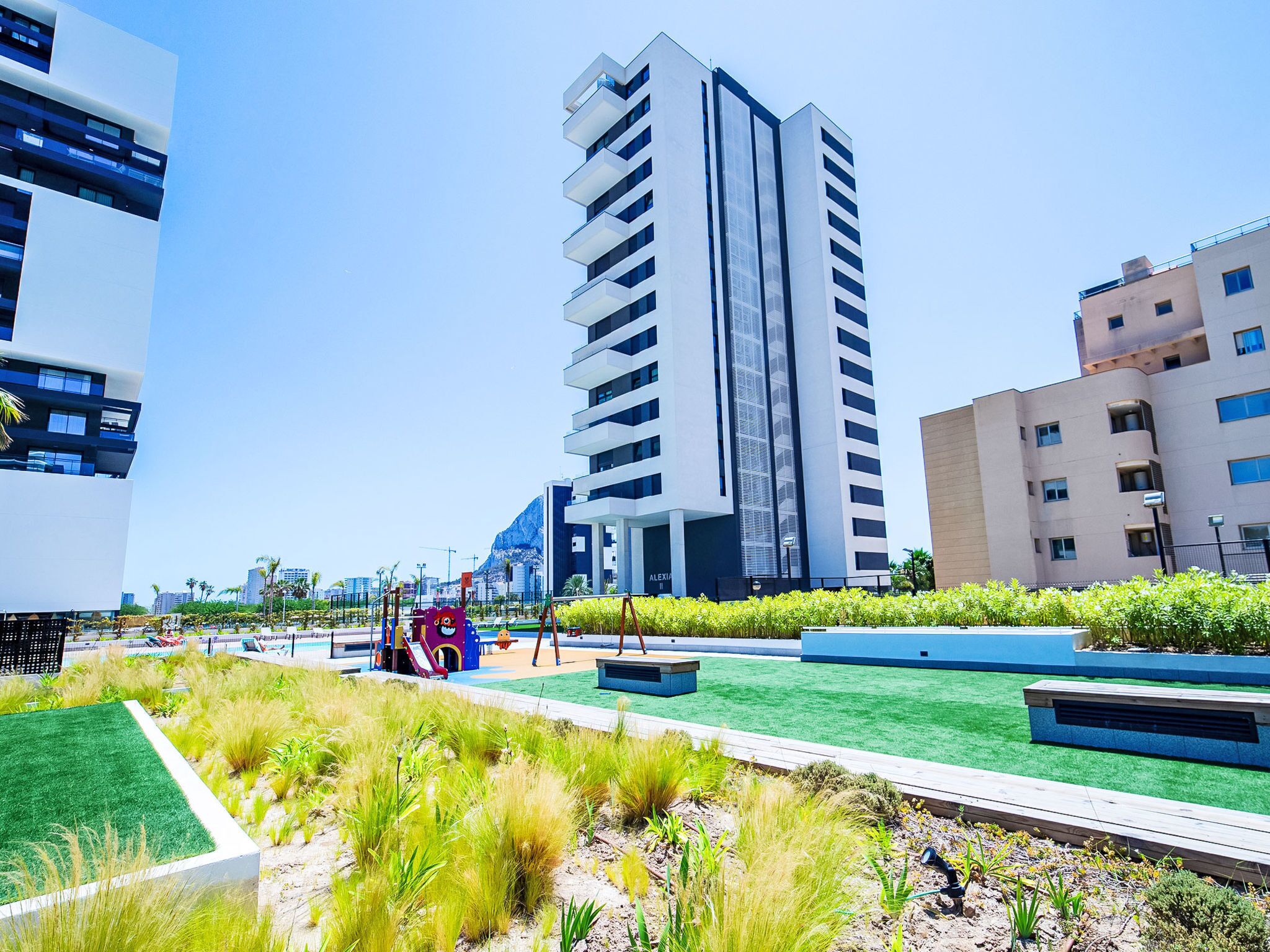 A modern urban landscape with high-rise buildings, a playground, and landscaped areas.