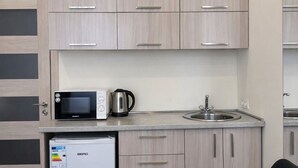 A compact kitchenette with a microwave, kettle, and refrigerator. - Fama 12 Hotel (Yerevan)