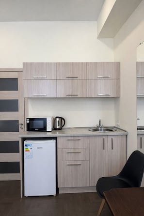 A compact kitchenette with a microwave, kettle, and refrigerator. - Fama 12 Hotel (Yerevan)