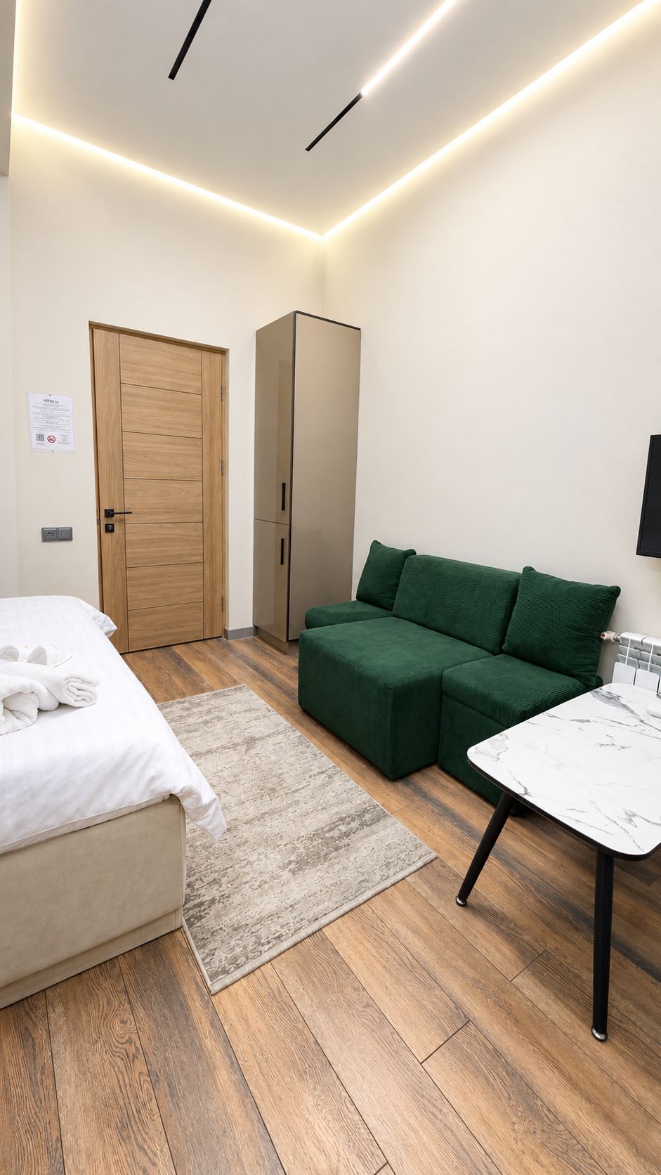Une chambre à coucher moderne avec un lit, un canapé vert et une petite table.