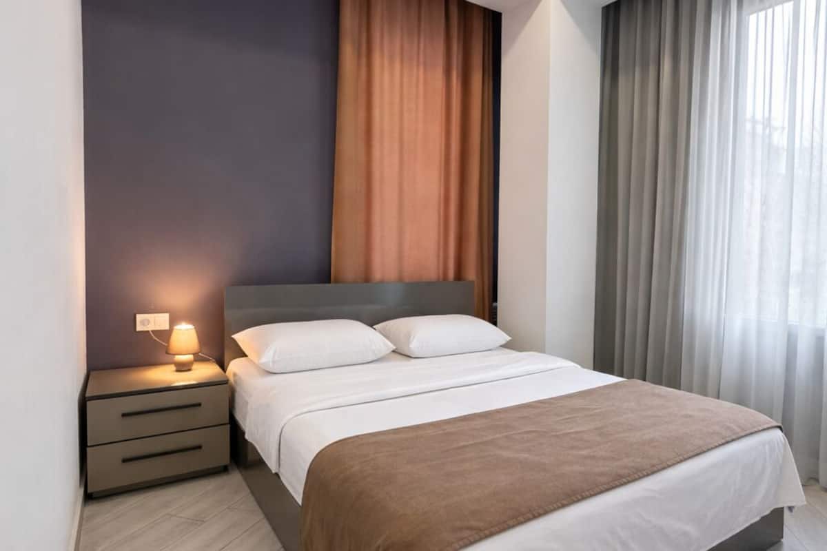 A modern bedroom with a bed, nightstand, and lamp.