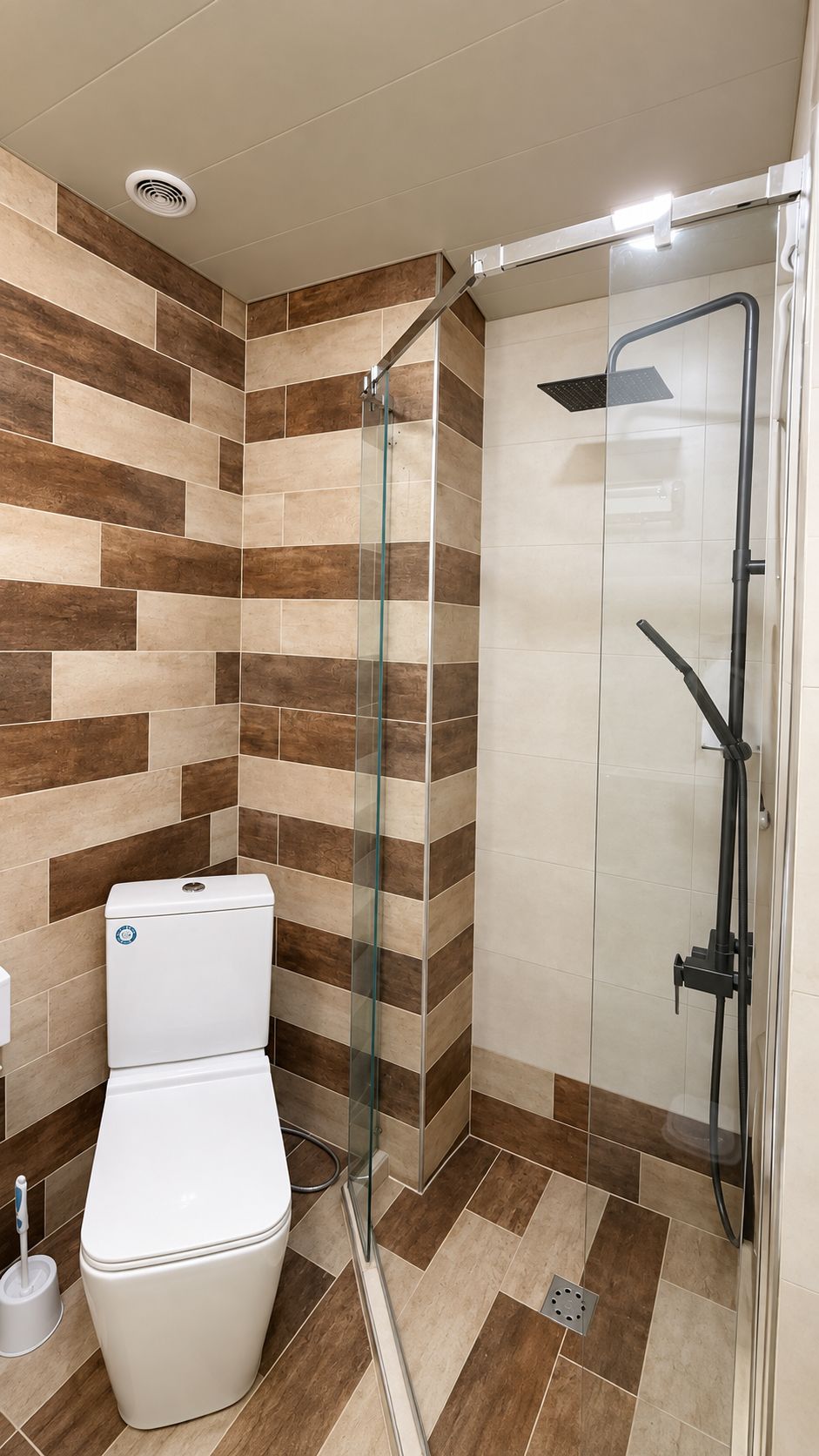 A bathroom with a glass-enclosed shower, a toilet, and a tiled floor.